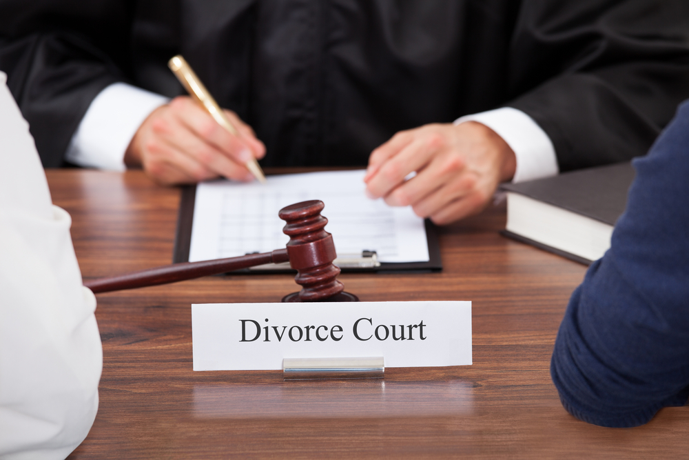 Cropped image of couple with judge writing at desk in court