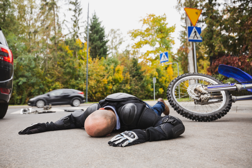 Dead motorcycle driver laying on the street next to his motorcycle