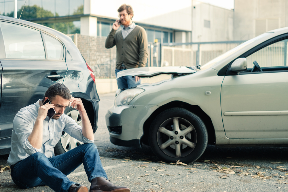 Two men calling car help assistance after an accident