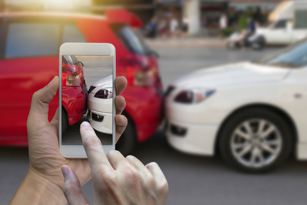 hand holding smartphone and take photo at The scene of a car crash and accident