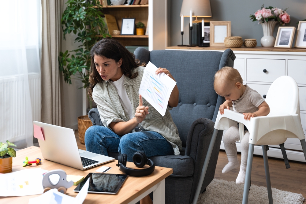Young single divorced mother with baby using laptop computer for video call with her lawyer