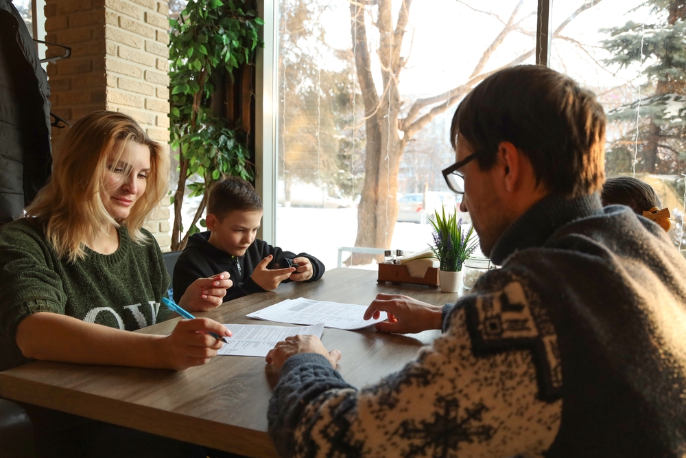 A married couple signs documents in a cafe
